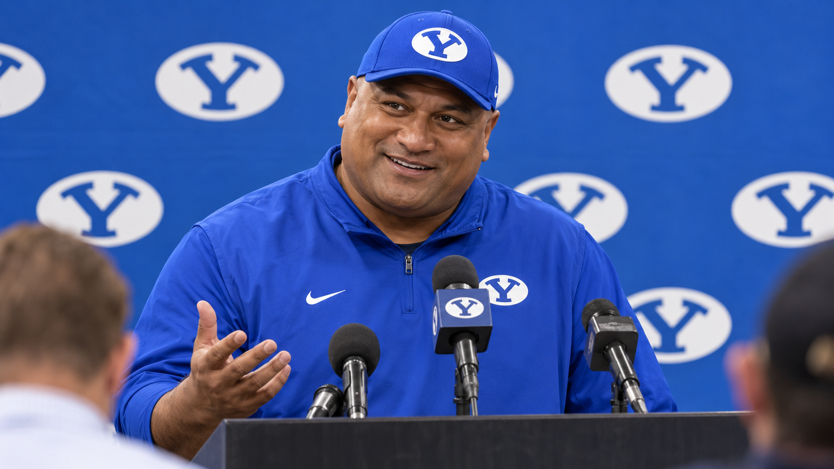 Satirical illustration of Kalani Sitake smiling during a BYU postgame press conference